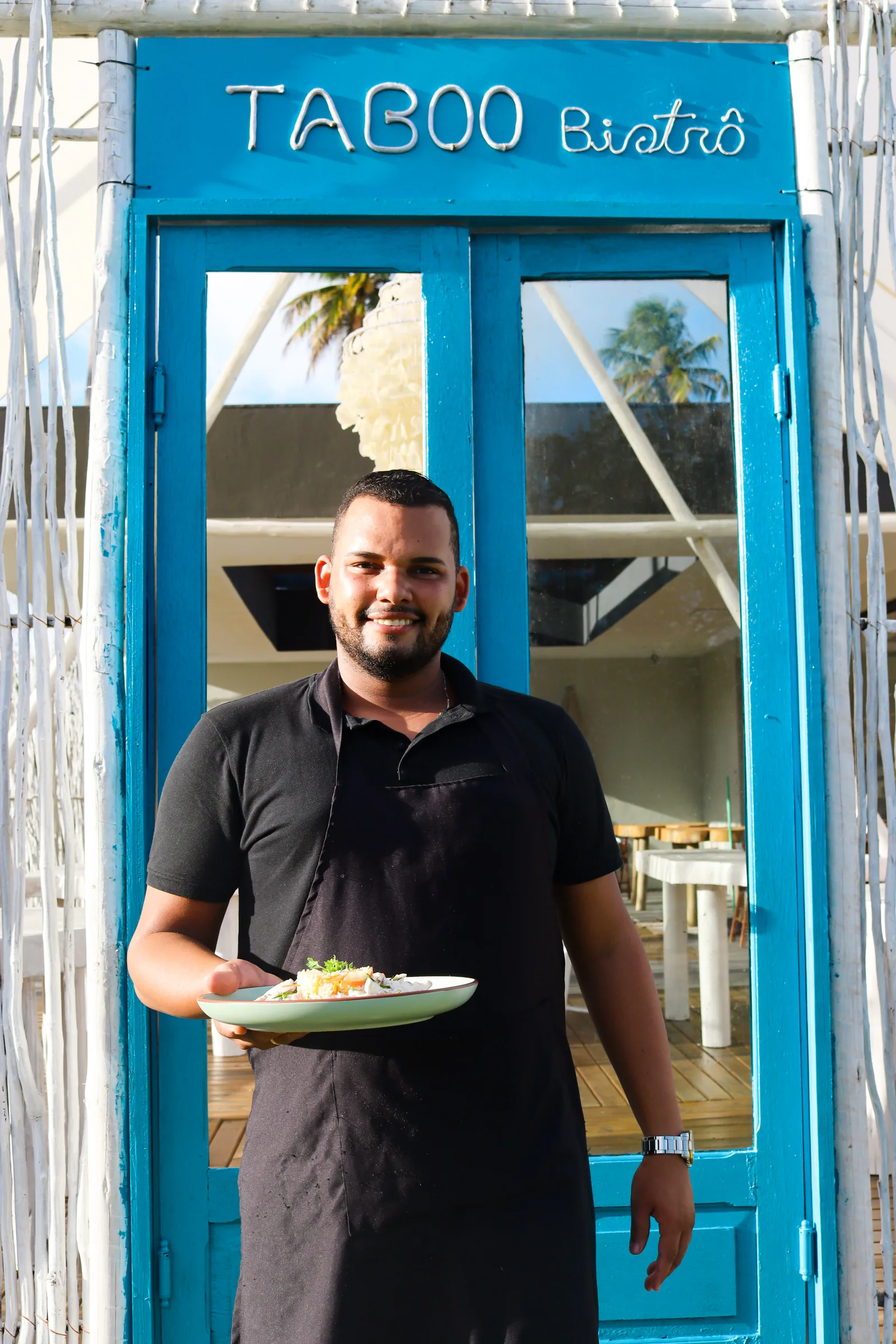 Un profesional de Taboo Bistrô presenta un plato en la entrada del restaurante.